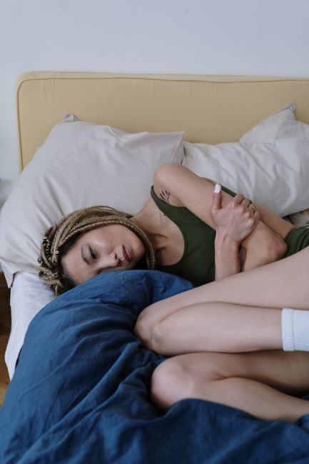 Person with back pain rolls to the side and pushes up from bed using both arms.
